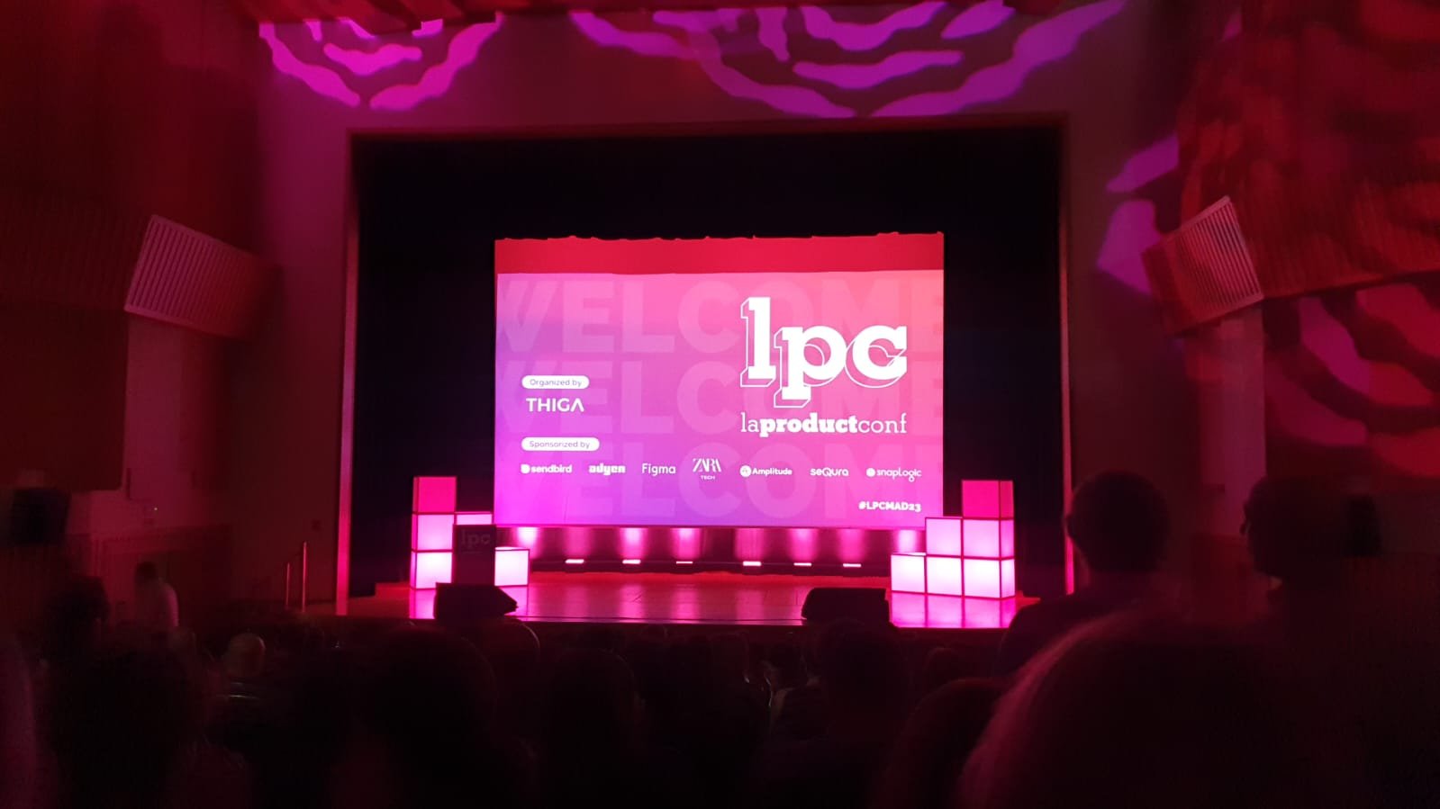 Auditorio de La Product Conf Madrid 2023 con la pantalla de bienvenida de laproductconf, organizada por THIGA y patrocinada por Sendbird, Adyen, Figma, Zara Tech, Amplitude, seQura y SnapLogic