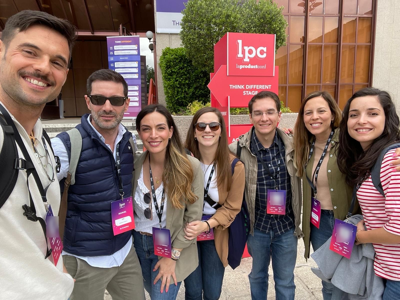 Parte del equipo de product managers de Genially sonriendo frente al cartel de La Product Conf, junto al Think Different Stage